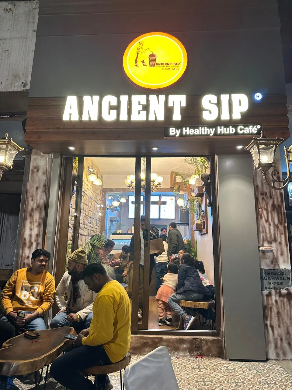 Ancient Sip storefront with an illuminated sign and customers seated outside